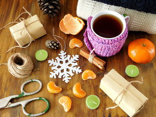 Mandarins, hot tea and present boxes on a wooden table. Process of wrapping the gifts