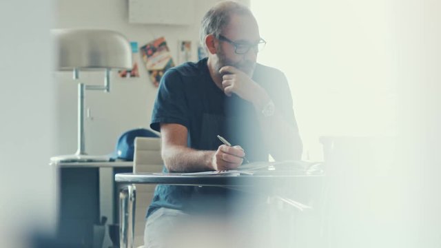 Narrow shot of a casual businessman working concentrated with his papers and documents on workdesk in modern office 