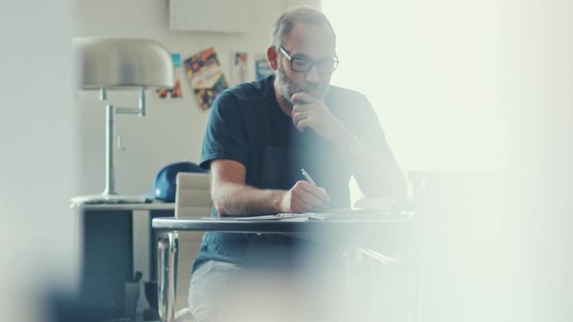 Narrow shot of a casual businessman working concentrated with his papers and documents on workdesk in modern office 