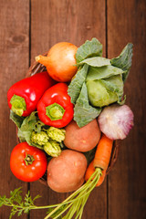Fresh vegetables lie in a basket on a wooden background. Bulgarian pepper, carrots, cabbage, potatoes and garlic on a wooden table. Thanksgiving Day. Background. Autumn harvest.