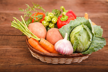 Fresh vegetables lie in a basket on a wooden background. Bulgarian pepper, carrots, cabbage, potatoes and garlic on a wooden table. Thanksgiving Day. Background. Autumn harvest.