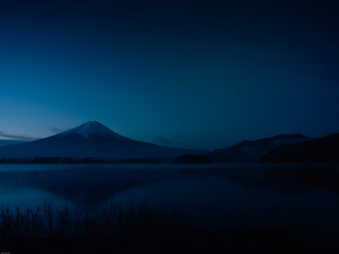landscape view from sunrise and haze on kawaguchi lake with motion blur from group of duck foreground and fuji mountain background with fog from japan