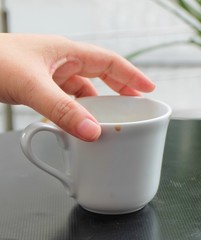 Hand Holding Empty Cup of Coffee on The Table