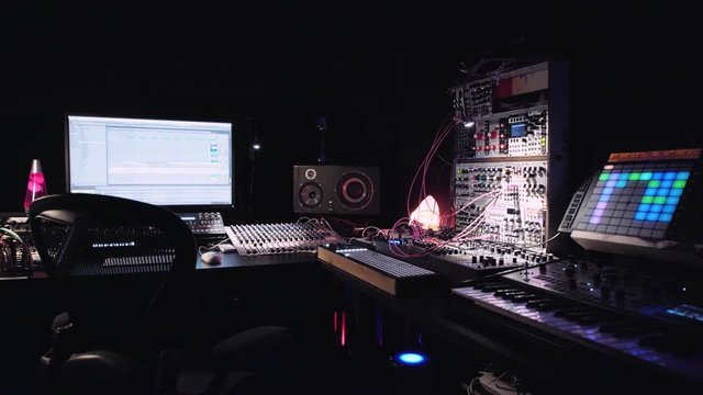 Empty work desk of professional audio sound engineer who creates music, computer desktop with recording software, blinking mixing lights of devices for postproduction