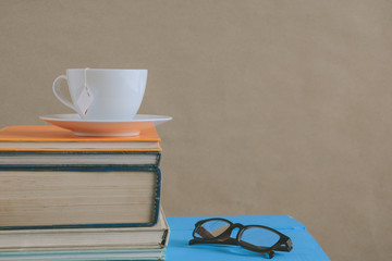 Book glasses and tea on the desk with study and education concept