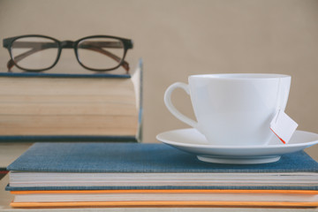 Book glasses and tea on the desk with study and education concept