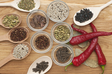Spices on a wooden board in glass bowls and wooden spoons