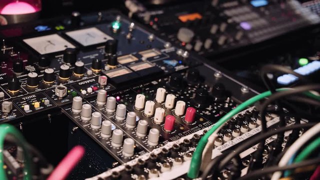 View on knobs, cords, gauges and blinking leds on music switcher board in professional sound production studio