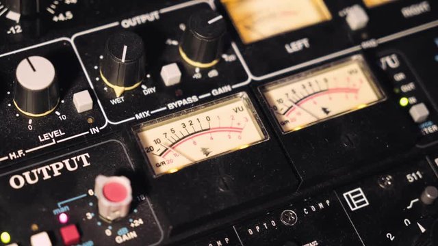 Top view on sound check output gauges moving rhytmically in tempo of music beat, located on professional sound board panel in production studio