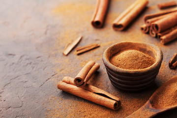 Cinnamon sticks and powder on brown rustic background. Aromatic spices.