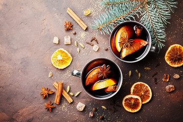 Two cups of christmas mulled wine or gluhwein with spices and orange slices on rustic table top view. Traditional drink on winter holiday.