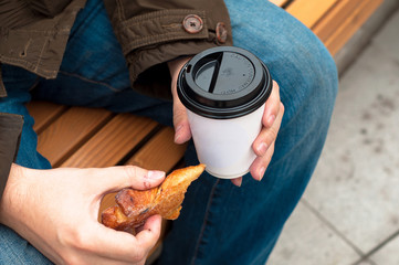 Hand holding coffee cup with croissant.