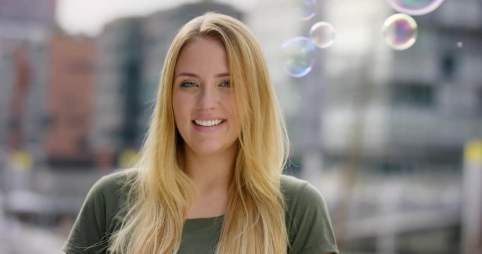 Attractive Girl gives a stunning smile to the camera while soap bubles float around her