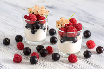 Raspberries and currants with dairy products on wooden white table.