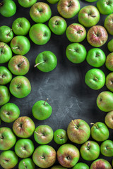 Green and red large colorful group of organic apples overhead on rustic black board in studio