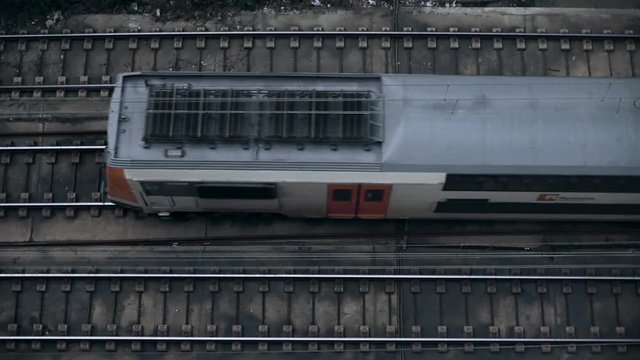 Slow motion top view shot of two deck or floor urban inter city train driving by pass rail tracks on gloomy grey day, concept commuting, office white collar life and everyday routine
