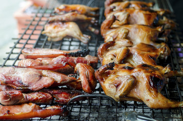 Chicken and pork grilled on a steel grate