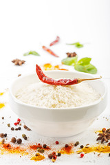 Рис в миске с различными специями и ингредиенты на белом фоне