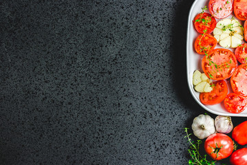 Tomatoes in a baking dish with garlic and herbs. Top view, space for text.