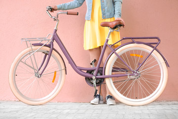 Fototapeta na wymiar Beautiful young woman with bicycle on color wall background