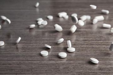 Scattering white pills on wooden table