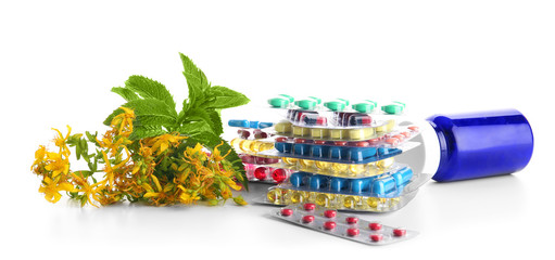 Blisters with colorful pills and herbs on white background