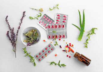 Blisters with colorful pills and herbs on white background