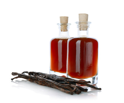 Bottles with vanilla extract and sticks on white background