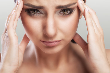 Fototapeta premium A beautiful woman on a gray background, stress and headache with migraine headaches, she wrestled with pain, a big portrait, high quality, professional makeup.