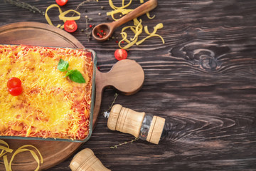 Delicious meat lasagna in baking dish on wooden table