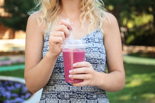 Woman with fresh smoothie outdoors