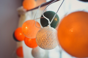 Cotton light balls in the home interior. Creative bright decoration for a home or office at Christmas. Orange, green, golden and white set.