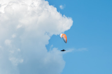 Paraglider flying in the blue sky against the background of clouds. Paragliding in the sky on a sunny day.