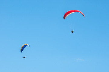 Two paragliders flying in the blue sky. Paragliding in the sky on a sunny summer day.