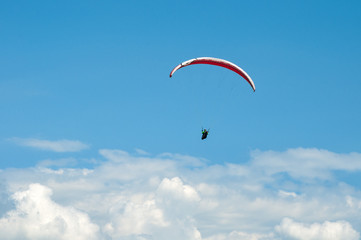 Paraglider flying in the blue sky against the background of clouds. Paragliding in the sky on a sunny day.