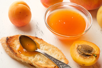 homemade jam of ripe peaches on a white wooden background