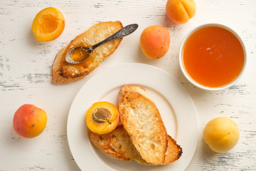 homemade jam of ripe peaches on a white wooden background