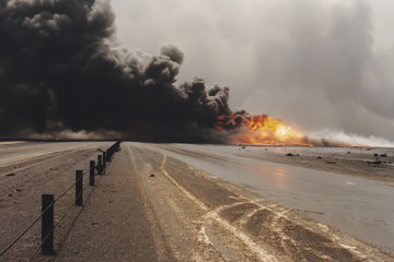 Road through oil well burning in field with oil slick, Kuwait