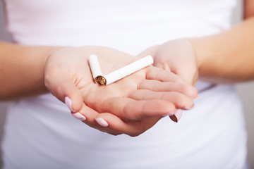Stop Smoking. Closeup Portrait Of Beautiful Smiling Woman Holding Cigarette In Hands, Breaking It In Half With Fingers. Quit Smoking Cigarettes Concept.