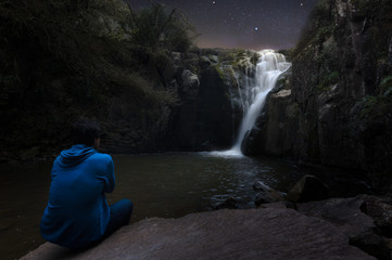 Man looking to stars near a waterfall - 171885837