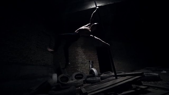 A strong guy performs a trick on a flying pylon in an abandoned building