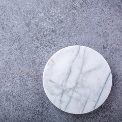 Gray concrete stone background texture with white marble cutting board. Top view.