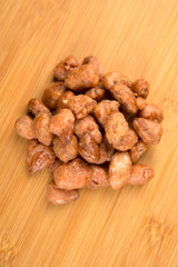 Pile of sugar roasted almonds on a wood background