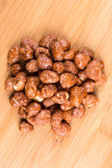Pile of sugar coated peanuts on a wood background