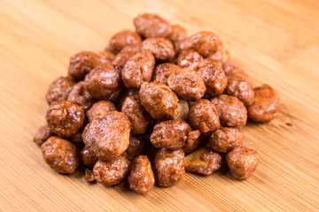 Pile of sugar coated peanuts on a wood background
