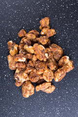 Pile of sugar coated pecans on a black background