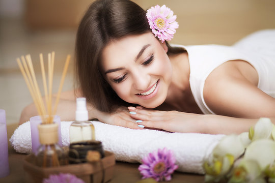 Woman At The Spa. Healthy Lifestyle And Relaxation Concept. A Beautiful Young Woman On A Massage Table. Aroma Oil And Butter. Spa Room.