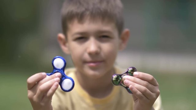 Happy Boy holding play two fidget spinners on nature