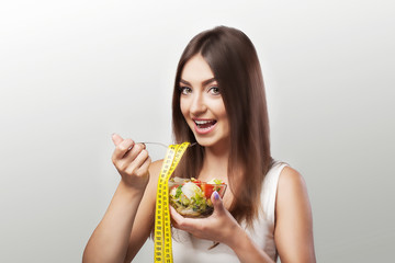 Healthy food. Smiling girl in sportswear holding a glass of salad and a fork. The concept of eating healthy and delicious food.