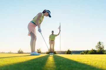 Frau auf dem Golfplatz übt Putting mit dem Golf Lehrer